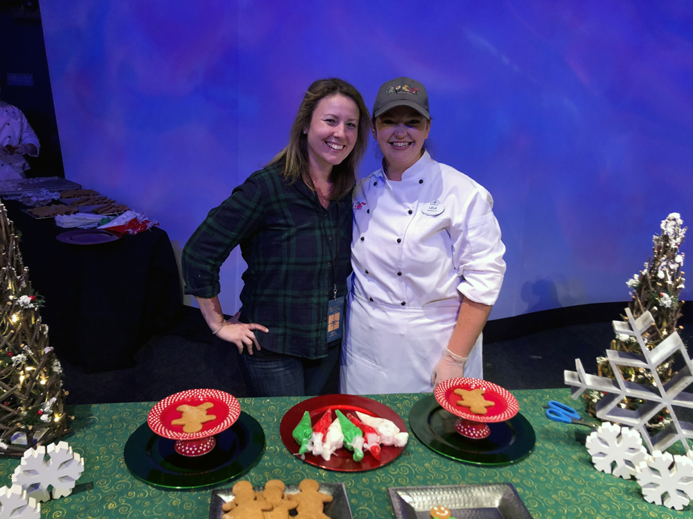 Two women in front of a table decorating Christmas Cookies