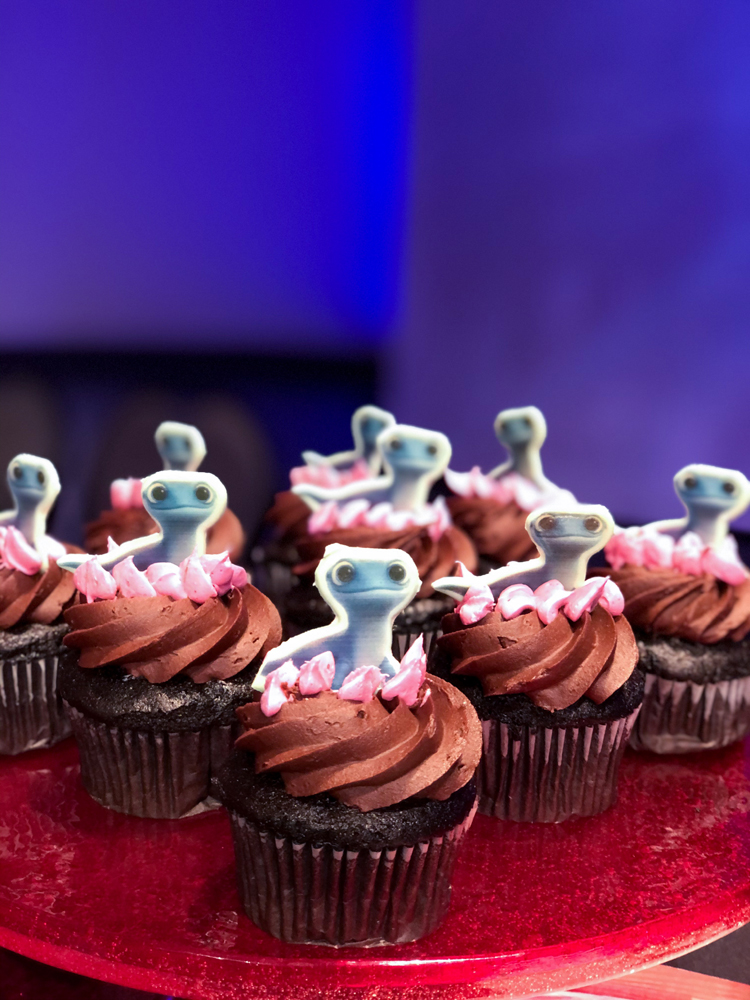 Brown chocolate cupcakes with a lizard topper on a red plate