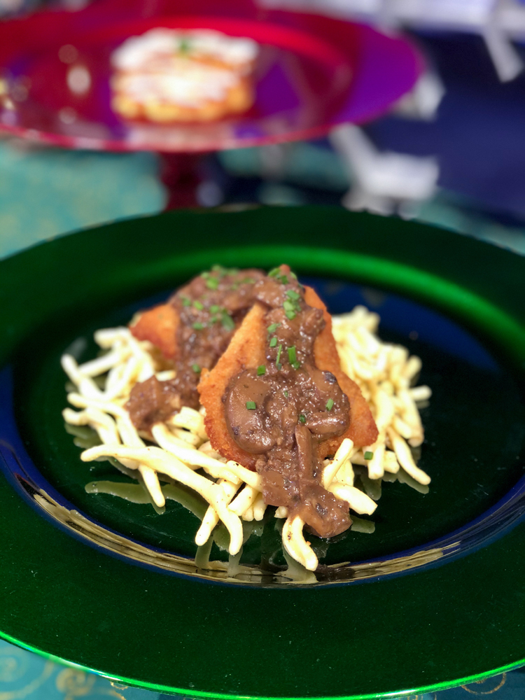 Brown pork with gravy and noodles on a green plate