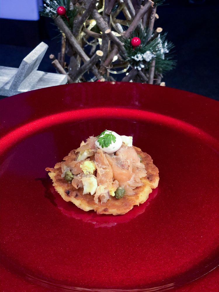 Pink salmon on brown potato latke on a red plate